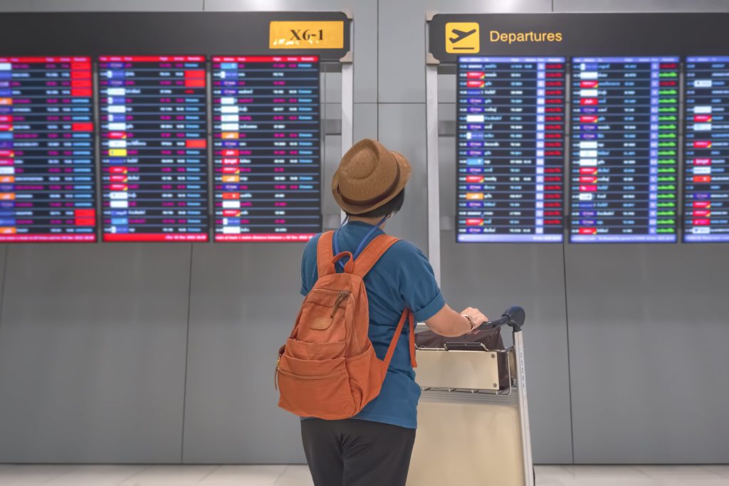 person looking at departures board at airport during their airport transfer