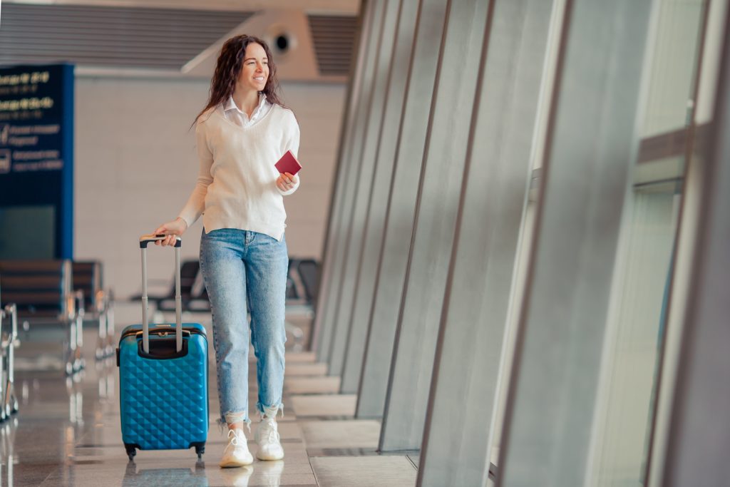 woman walking around airport with carry-on luggage during an airport transfer